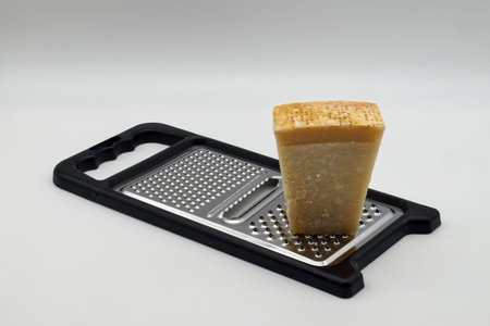 Metal grater with Parmigiano Reggiano cheese isolated on white background.の写真素材