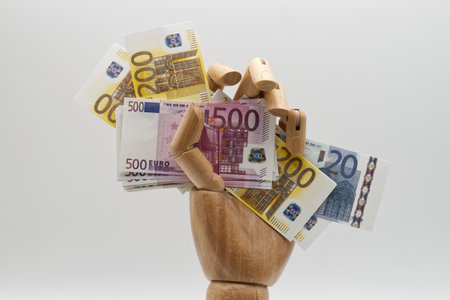 Wooden hand holding Euro banknotes on white background. Business conceptの写真素材