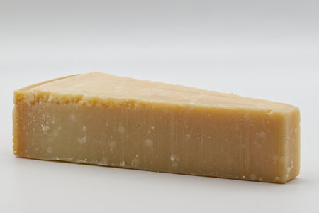 A single slice of Parmigiano Reggiano Cheese on a white background. A generous wedge of authentic Parmigiano Reggiano, parmesan cheese, freshly cut and ready for grating, slicing, or enjoying on its own.の写真素材