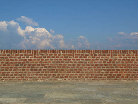 A wall with blue sky with clouds behind