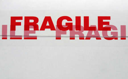 Fragile warning sign label tag on a cardboard box packet parcel for mail post shippingの写真素材