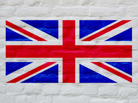 Union Jack national flag of United Kingdom over white bricks wall backgroundの写真素材
