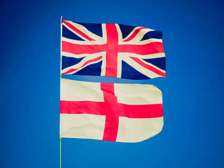 Vintage retro looking Flag of the UK (Union Jack) and flag of England over a blue skyの写真素材