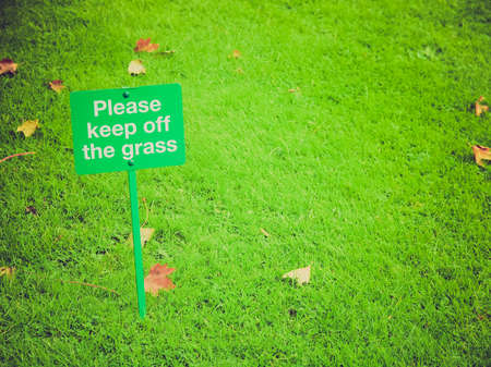 Vintage looking Please keep off the grass sign in a meadowの写真素材