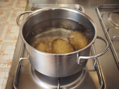 Boiling potatoes in a saucepot on a gas cookerの写真素材