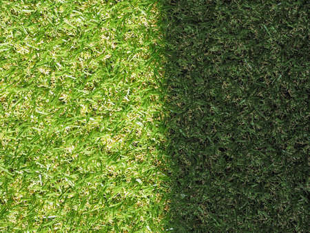 Green artificial synthetic grass meadow texture useful as a background - sunny and shadow spotの写真素材