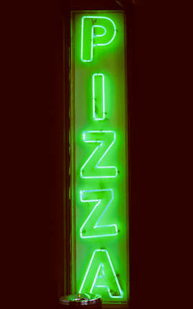 Vintage looking Green neon light pizza sign marking a pizzeria restaurantの写真素材