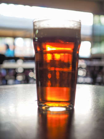 A pint of beer in a pub, focus on beer and blurred background bokehの写真素材