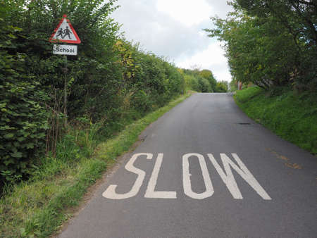 Slow sign painted on tarmac on a british road near a schoolの写真素材