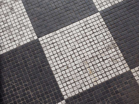 Checkered black and white mosaic stone pavement useful as a backgroundの写真素材