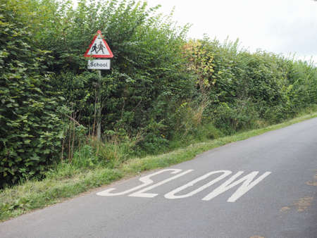 Slow sign painted on tarmac on a british road near a school