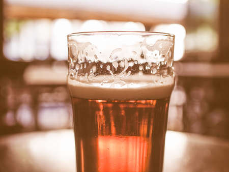 Vintage looking A pint of beer in a pub, focus on beer and blurred background bokehの写真素材