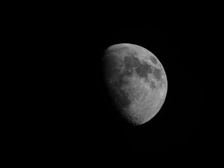Gibbous moon over dark black sky seen with a telescope from northern emisphere at night in black and whiteの写真素材