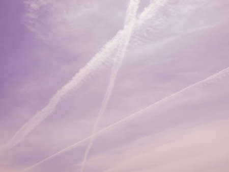 Blue sky with plane trail and white clouds useful as a background vintage