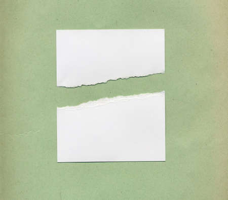 Torn paper note over green paper backgroundの写真素材