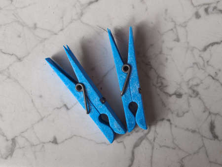 Clothespin or clothes peg spring loaded clamp on white marble top