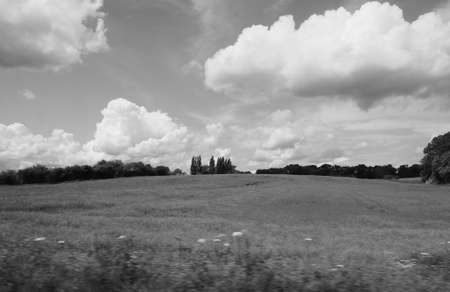 English countryside seen from a train to London, with selective focus on the horizon and motion blur on the foreground in black and whiteの写真素材