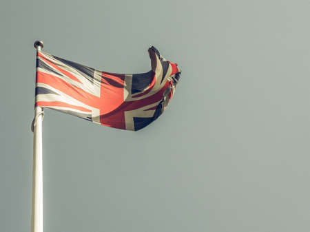 Vintage looking The national flag of United Kingdom, Europe floating in the wind over blue skyの写真素材