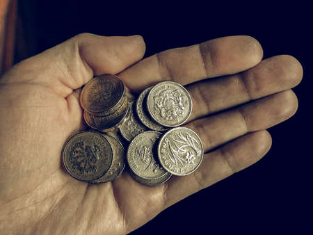 Vintage looking Hand with British Pound coins currency of the United Kingdomの写真素材