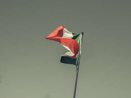 Vintage looking The national flag of Italy, Europe floating over blue skyの写真素材