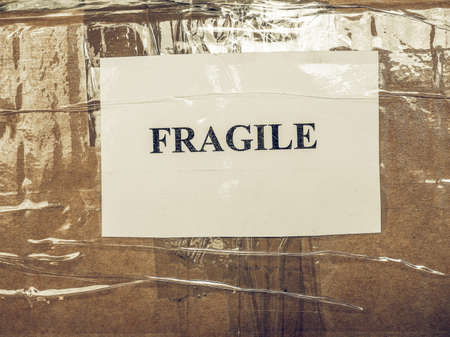 Vintage looking Fragile warning label tag on a cardboard box packet parcel for mail post shippingの写真素材