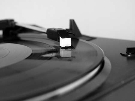 Vinyl record spinning on a turntable, focus on needle - in black and white