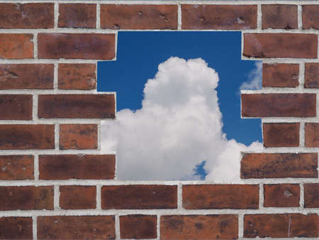 A hole in a Red brick wall with skyの写真素材