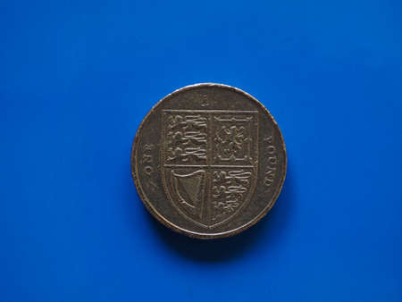One Pound (GBP) coin, currency of United Kingdom (UK) over blue background