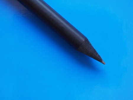 black pencil over blue paper texture background with copy spaceの写真素材