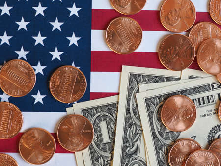 One Dollar banknotes and One Cent coins (USD) currency money over the flag of the United States