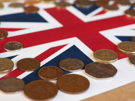 Pound coins money (GBP), currency of United Kingdom, over the Union Jack