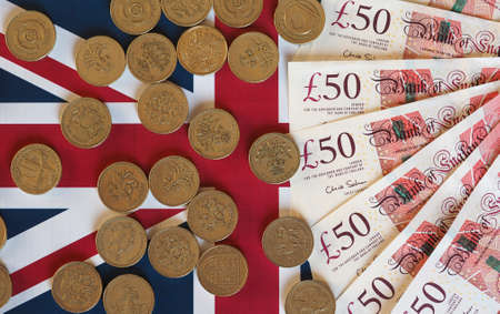 Pound coins and banknotes money (GBP), currency of United Kingdom, over the Union Jack