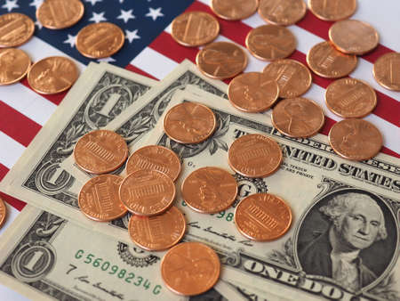 One Dollar banknotes and One Cent coins (USD) currency money over the flag of the United Statesの写真素材