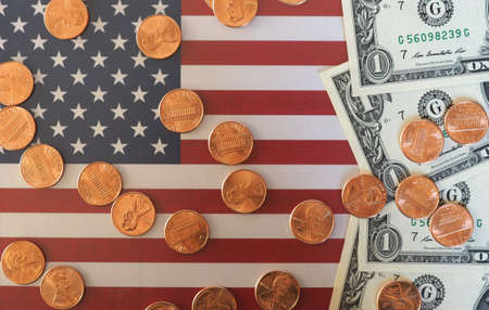 One Dollar banknotes and One Cent coins (USD) currency money over the flag of the United Statesの写真素材