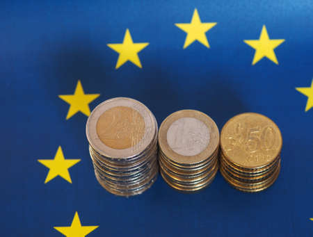 Euro coins (EUR), currency of European Union over flag of Europeの写真素材