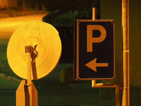 parking traffic sign with mirror at night with high pressure orange street lightingの写真素材
