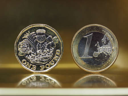 1 pound and 1 euro coin money over metallic backgroundの写真素材