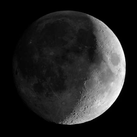 waxing crescent moon seen with an astronomical telescope - square 1:1 format close crop in black and...