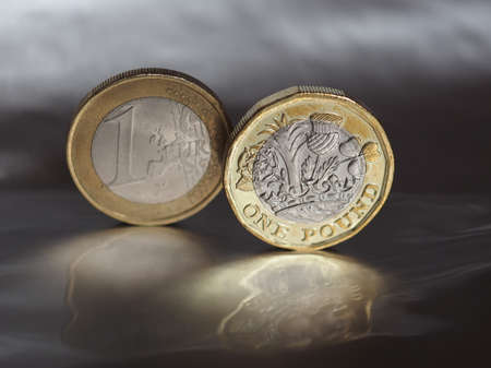 1 pound and 1 euro coin money over metallic backgroundの写真素材