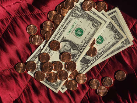 One Dollar banknotes and One Cent coin money (USD), currency of United States over crimson red...