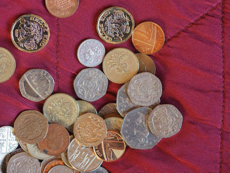 Pound coins money (GBP), currency of United Kingdom over crimson red velvet backgroundの写真素材