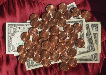 One Dollar banknotes and One Cent coin money (USD), currency of United States over crimson red velvet backgroundの写真素材