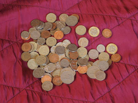 Pound coins money (GBP), currency of United Kingdom over crimson red velvet backgroundの写真素材