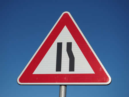Warning signs, road narrows traffic sign over blue skyの写真素材