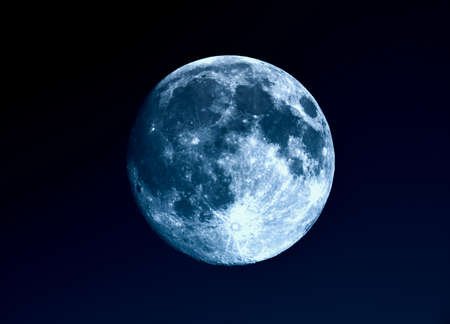 High contrast Full moon seen with an astronomical telescope over blue skyの写真素材