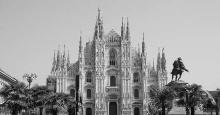 Duomo di Milano (meaning Milan Cathedral) church with palm trees in Milan, Italy in black and white