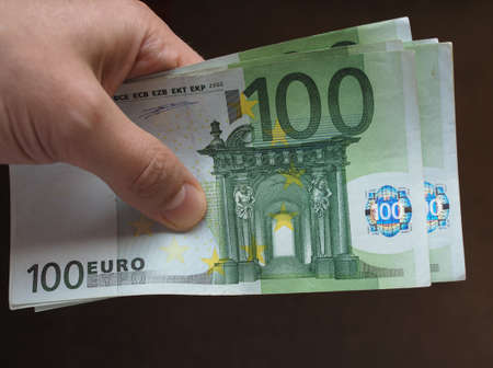 Hand holding and giving Euro banknotes money (EUR), currency of European Union