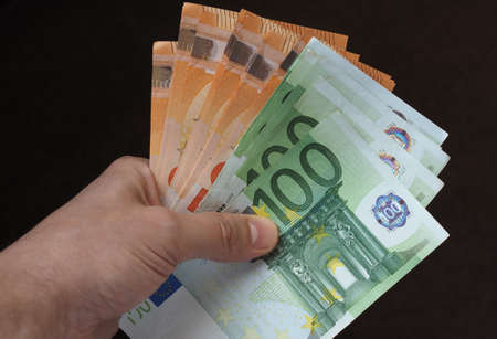 Hand holding and giving Euro banknotes money (EUR), currency of European Unionの写真素材