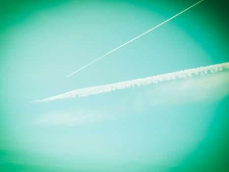 Blue sky with plane trail and white clouds useful as a background vintage retroの写真素材