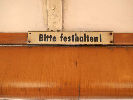 Bitte festhalten (meaning Please hold tight) sign on vintage German tramの写真素材